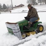 creative-man-plows-snow-covered-driveway-with-riding-lawnmower-and-a-large-cardboard-tv-box.jpg