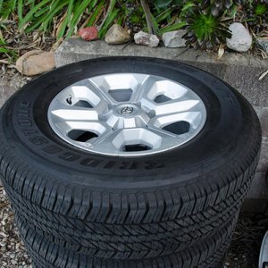4x 265/70/17 Bridgestone Dueler H/T tires, stock wheels, caps and lugs