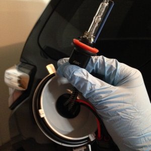 Put your gloves on and "thread" the bulb through the dust cover.  The bulbs have a nice rubber grommet that you will need to finagle into place to sto