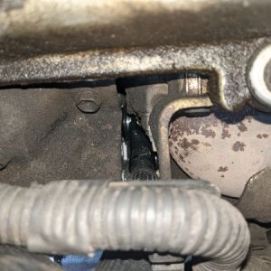 On the driver's side below the valve cover and header, the positive connection for the alternator is barely visible.