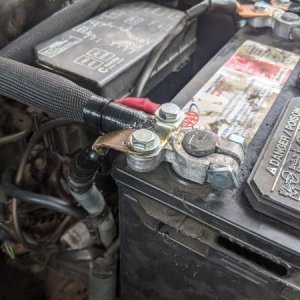 View of the positive battery terminal with the factory wires bolted in on either side.