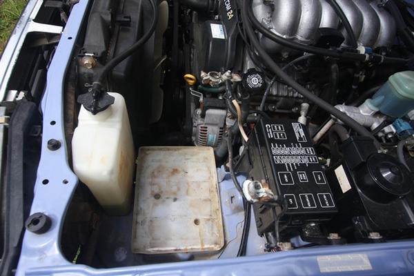 closeup of battery area and radiator overflow bottle