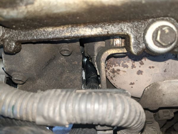 On the driver's side below the valve cover and header, the positive connection for the alternator is barely visible.