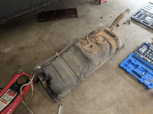 PO decided for whatever reason that instead of dropping the tank, they would take some tin snips to the floorboard and toss the plastic cap while they