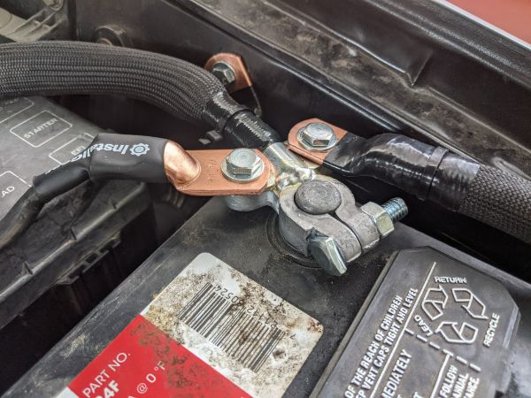 View of the negative battery terminal with the factory ground and battery negative to chassis wires bolted on either side. I also removed the paint wh