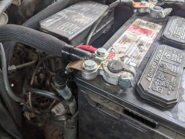 View of the positive battery terminal with the factory wires bolted in on either side.